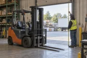 Supervisor checking doorway clearance beside a parked forklift